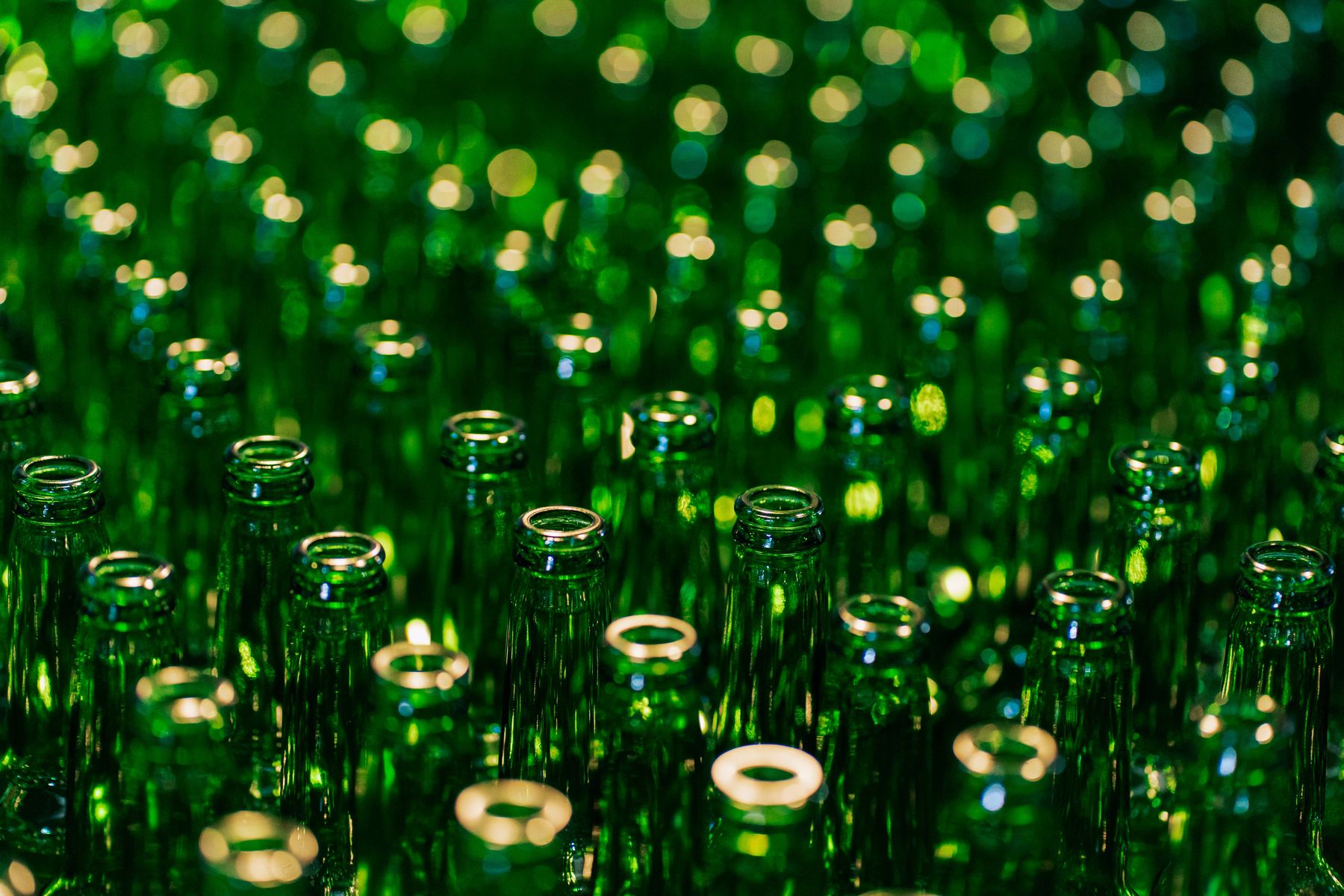Close-up of open green glass bottle mouths; stock detail illustrating bottle finishes